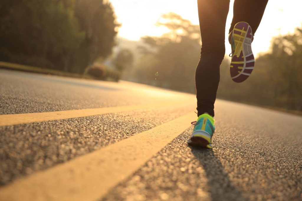 Frau joggt auf Straße bei Sonnenaufgang